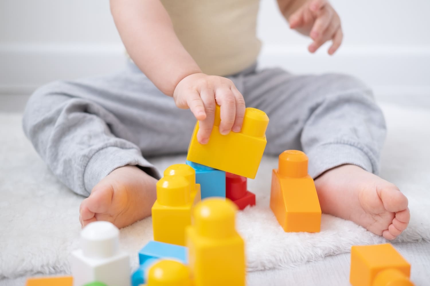 Bebé sentado jugando con bloques de construcción de colores.