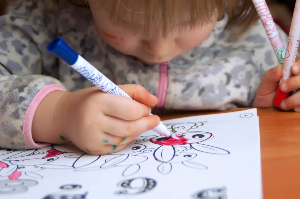 Niño pequeño concentrado en colorear con marcadores.