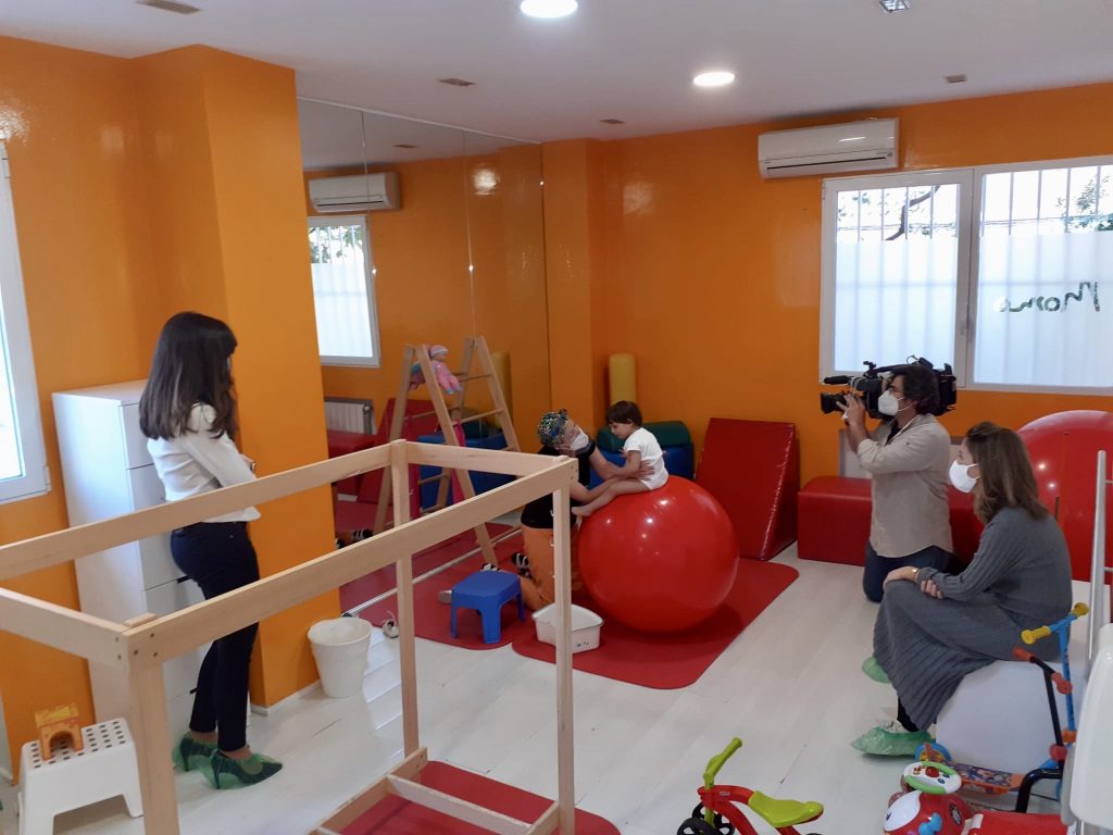 Una sala de terapia ocupacional para niños con una persona filmando una sesión de ejercicio.